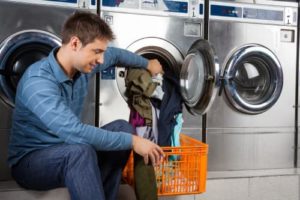 Man in laundromat sorting through his laundry